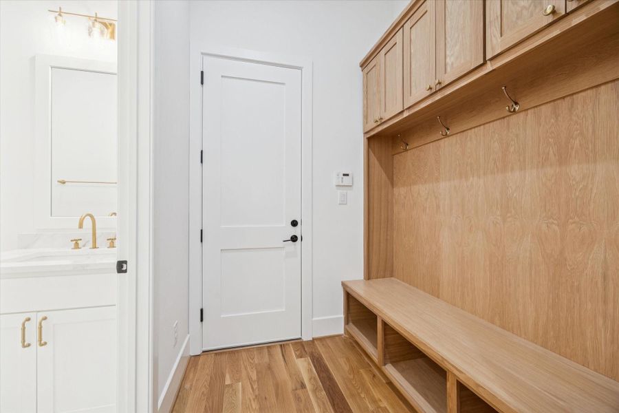 White oak cabinetry creates a highly functional mudroom designed to keep daily routines organized. Built in bench seating, overhead storage, and easy access to the garage and nearby bath support busy households while maintaining a clean, polished look. Quick access to the half bath. White oak cabinetry creates a highly functional mudroom designed to keep daily routines organized. Built in bench seating, overhead storage, and easy access to the garage and nearby bath support busy households while maintaining a clean, polished look. Quick access to the half bath.