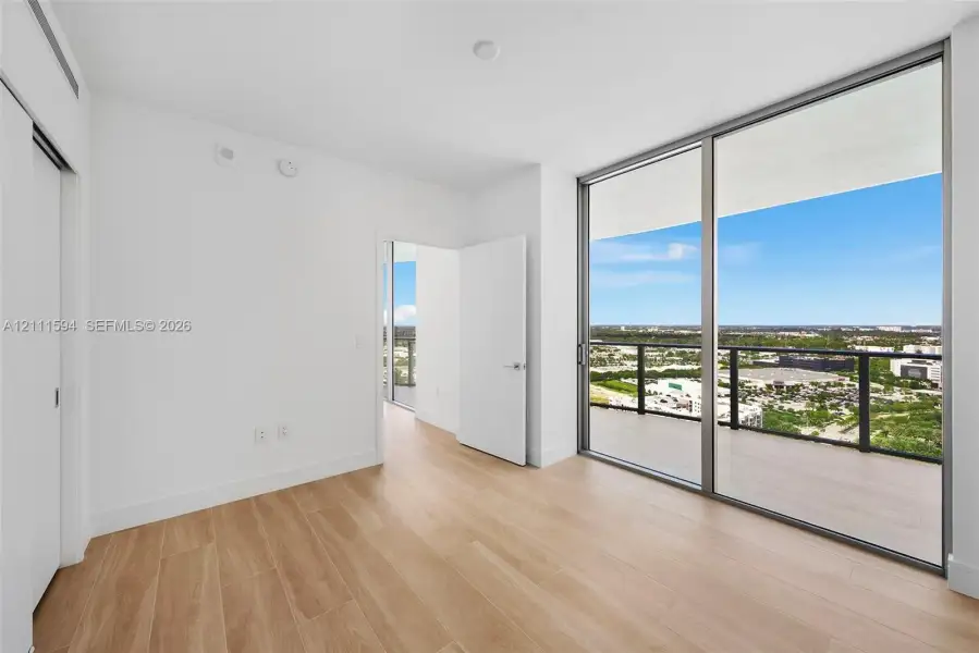 Floor-to-ceiling glass windows, private balcony with metal railing, wood-finish flooring, and crisp white wall finishes Floor-to-ceiling glass windows, private balcony with metal railing, wood-finish flooring, and crisp white wall finishes