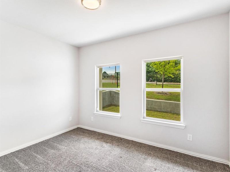 Bright room featuring two large windows, neutral gray carpet, white walls, white baseboards, and a flush-mount ceiling light fixture