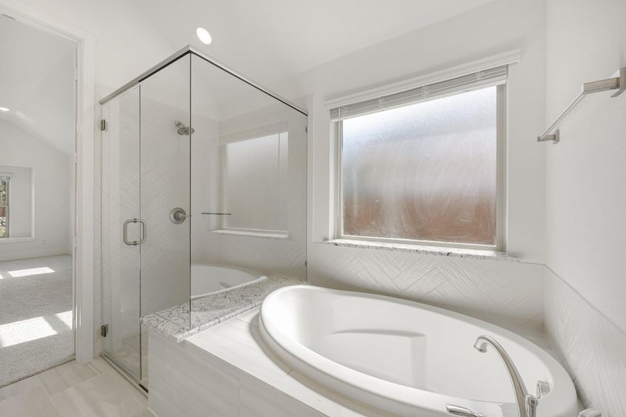 White bathroom with soaking tub, glass-enclosed shower, and herringbone tile walls White bathroom with soaking tub, glass-enclosed shower, and herringbone tile walls