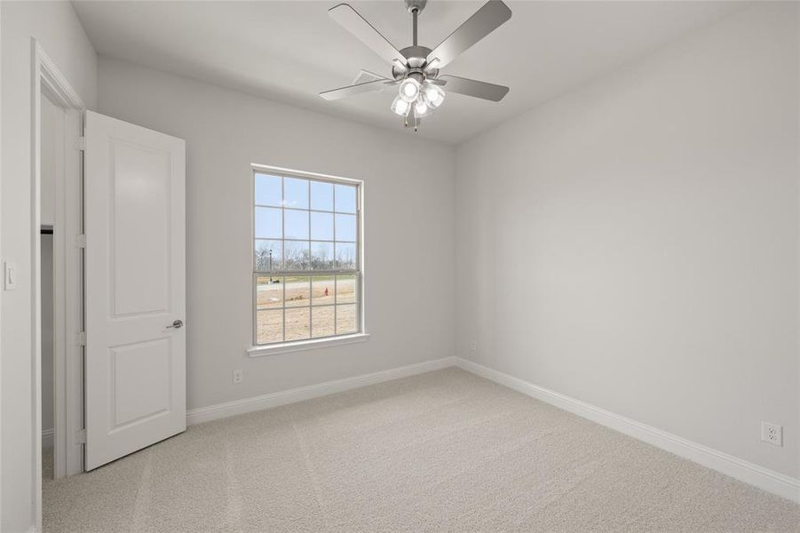 Carpeted empty room with baseboards and ceiling fan Carpeted empty room with baseboards and ceiling fan