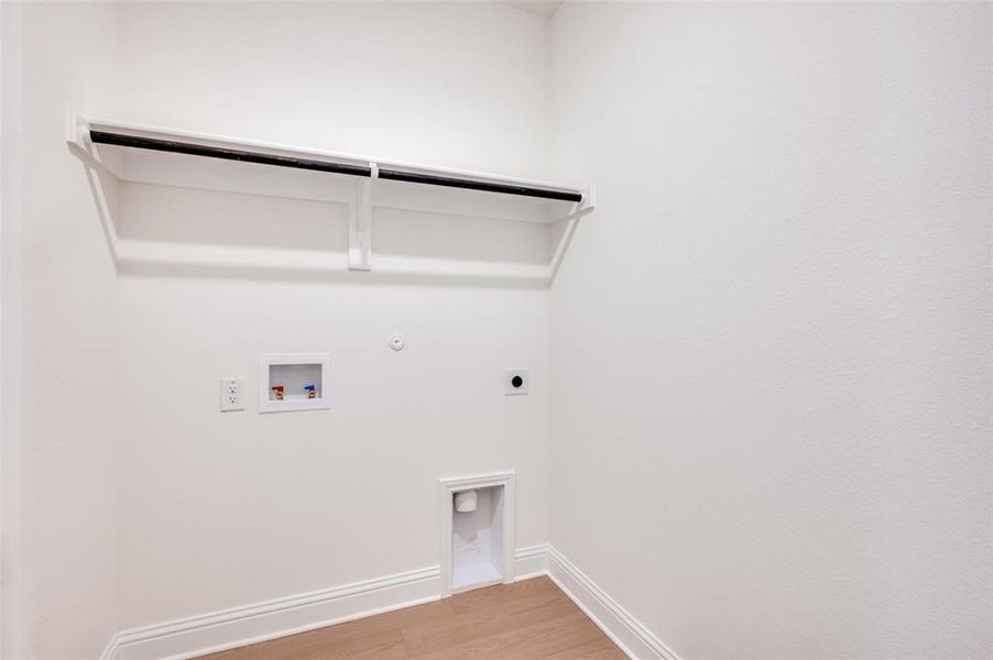 Washroom with hookup for a gas dryer, electric dryer hookup, hookup for a washing machine, and light wood-type flooring