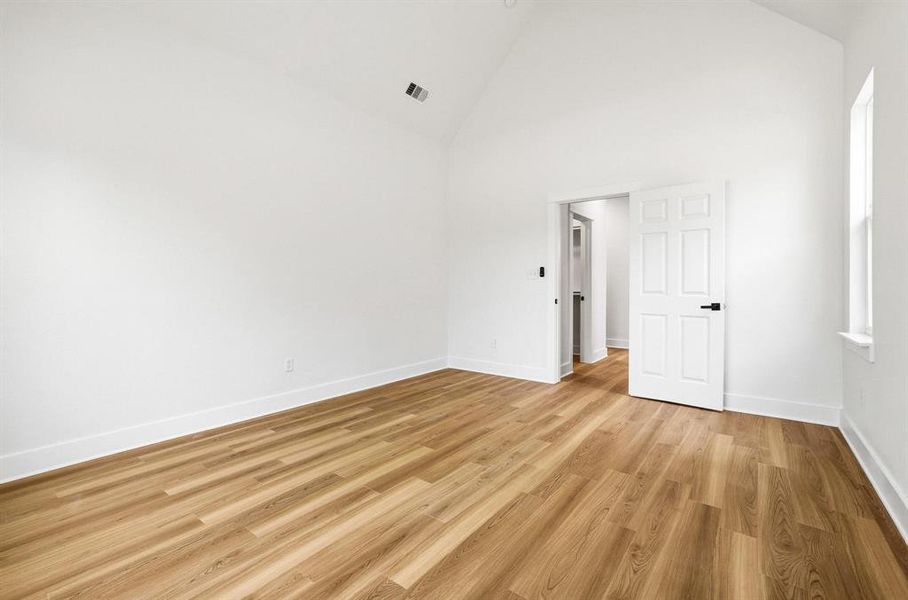 Bright interior space featuring wood-finish flooring, white walls, and a vaulted ceiling Bright interior space featuring wood-finish flooring, white walls, and a vaulted ceiling