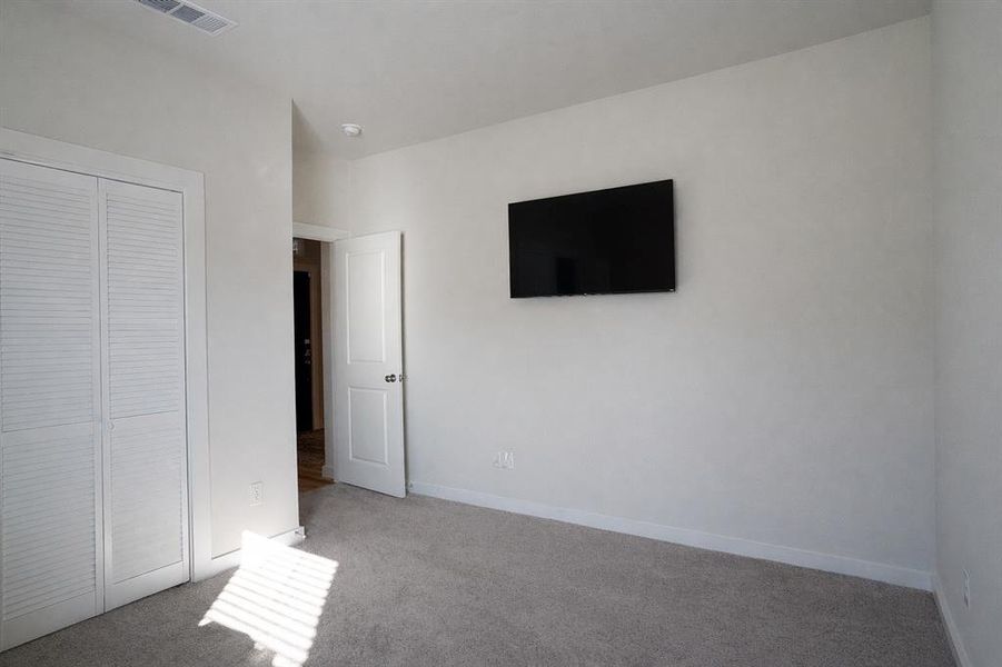 Carpeted room featuring a white interior door, louvered closet doors, and recessed lighting
