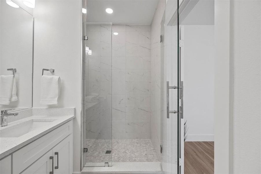 Full bathroom featuring recessed lighting, a shower stall, vanity, wood finished floors, and baseboards