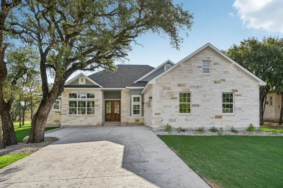 View of front of house featuring a front yard, stone siding, french doors, driveway, and a shingled roof