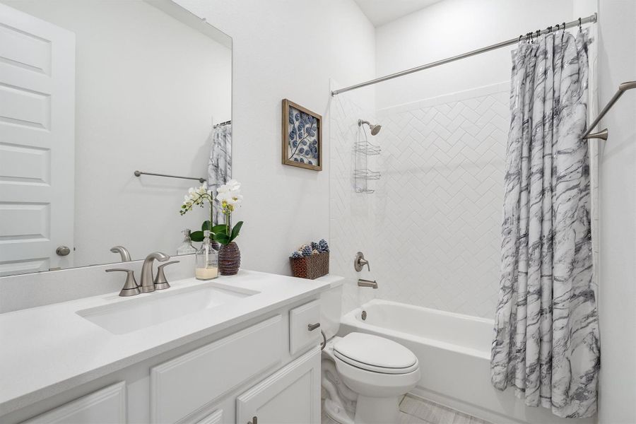 This bathroom offers a sleek white sink vanity, a convenient shower/tub combo, and a modern toilet — designed for both style and everyday comfort.