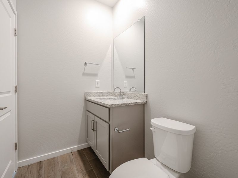 A bathroom with a sink toilet and mirror.