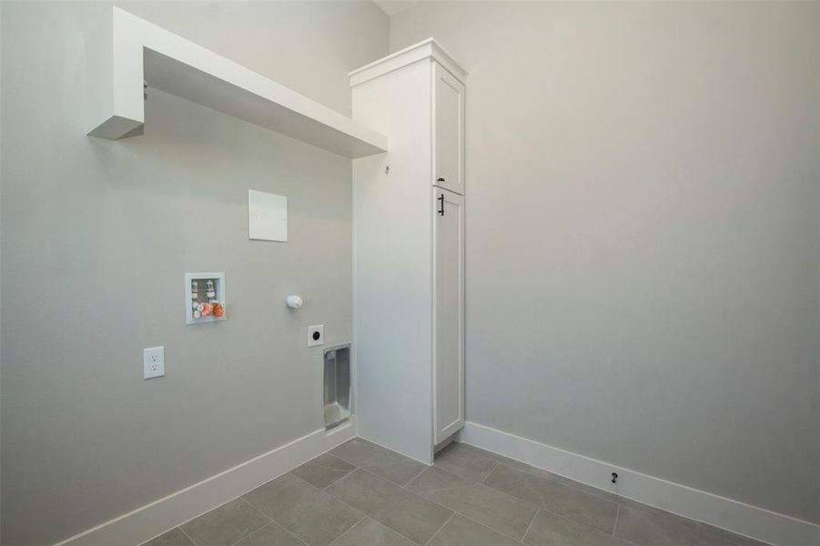 Laundry area with hookup for a washing machine, light tile patterned floors, and hookup for an electric dryer