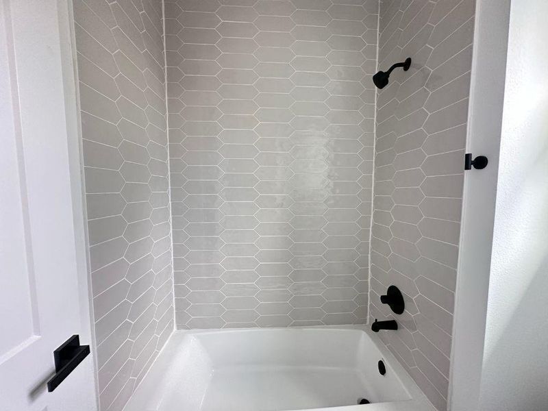 A pristine bath and shower area features stylish geometric tile work. A pristine bath and shower area features stylish geometric tile work.