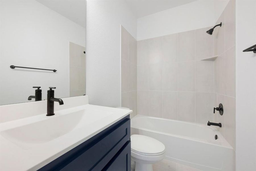 Bathroom featuring a white vanity countertop, matte black fixtures, a built-in bathtub with shower, light-colored subway tile surround, and a recessed shower shelf