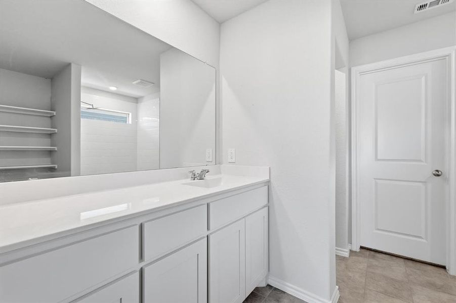 Bathroom with vanity, and light tile, patterned floors and door to walk-in closet Bathroom with vanity, and light tile, patterned floors and door to walk-in closet