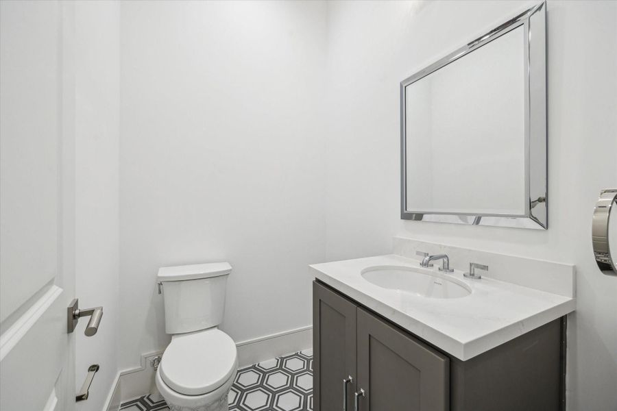 Conveniently located off of the third-floor flex space is a powder room featuring Biancone Quartz countertops and Adex hexagonal decorative floor tiles. Conveniently located off of the third-floor flex space is a powder room featuring Biancone Quartz countertops and Adex hexagonal decorative floor tiles.