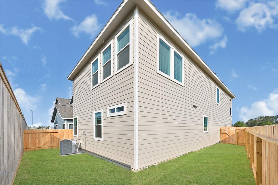 This image shows the side view of a two-story house with siding and several windows for natural light. The property is enclosed by a wooden fence.Please note: The image is not the actual home; it is a home with the same floor plan in the neighborhood.