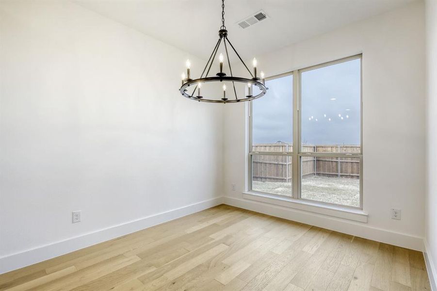 Unfurnished dining area with a chandelier and light wood-type flooring