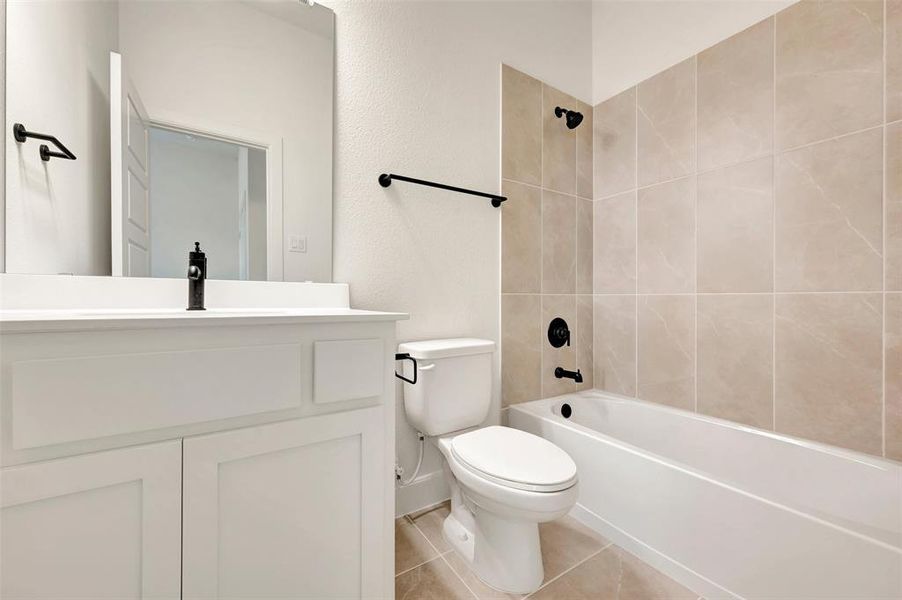 Modern bathroom featuring a white vanity with a black faucet, a built-in tub with a shower, and light-toned wall and floor tile