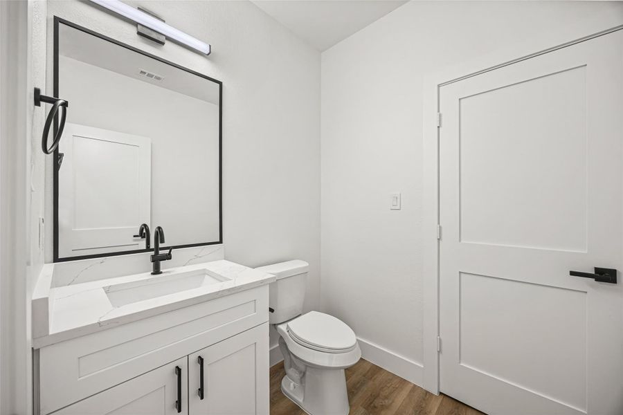 Contemporary vanity with quartz countertop, framed mirror, and matte black fixtures.