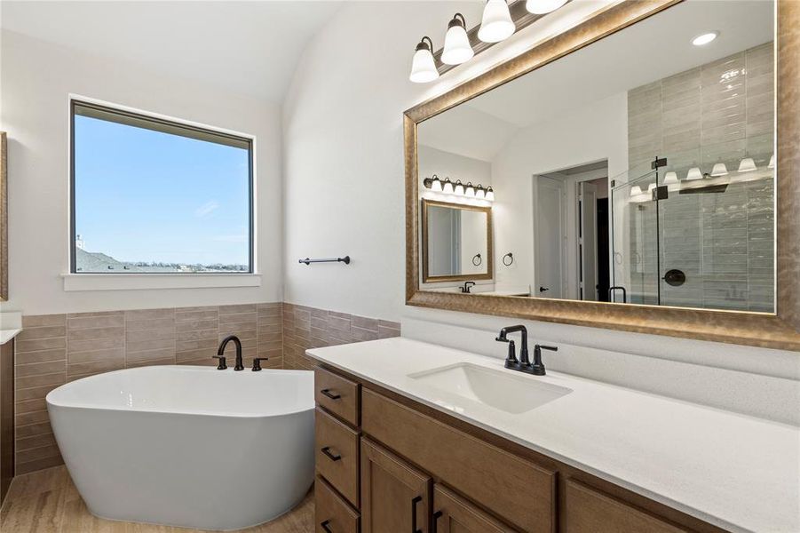 Bathroom featuring plus walk in shower, vaulted ceiling, tile walls, and vanity