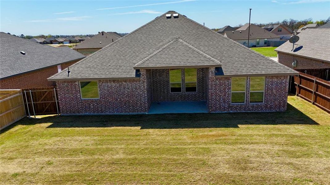 Back of property with a fenced backyard, a residential view, brick siding, roof with shingles, and a patio