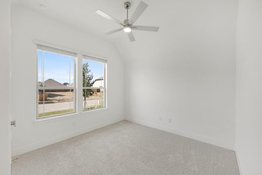 Empty bedroom with vaulted ceiling, ceiling fan, carpet flooring, and two windows Empty bedroom with vaulted ceiling, ceiling fan, carpet flooring, and two windows