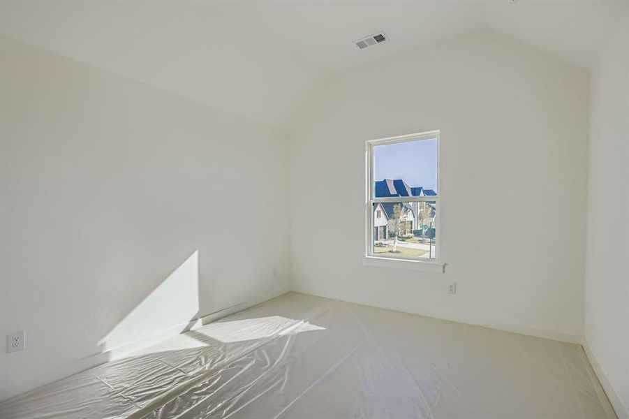 Unfurnished room featuring lofted ceiling and baseboards