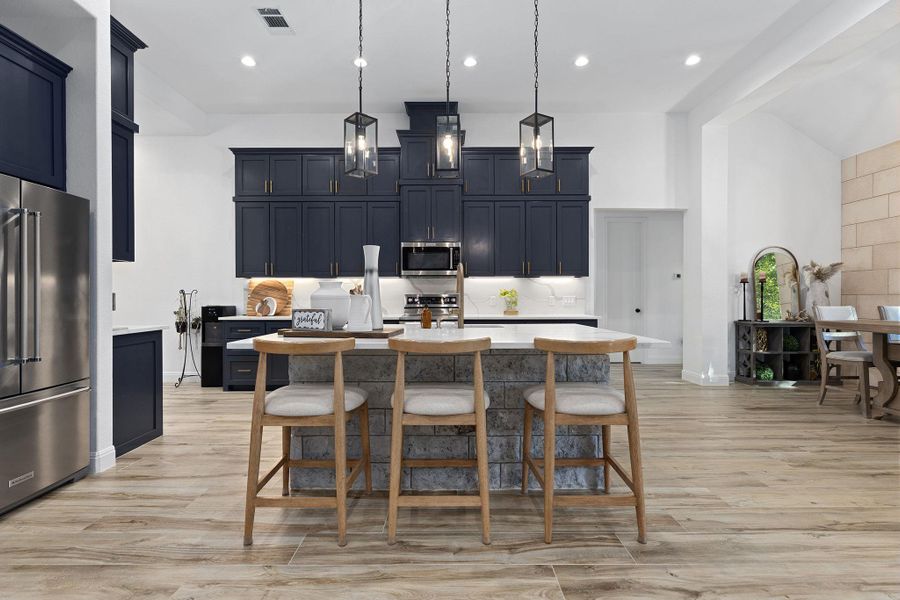 Kitchen featuring pendant lighting, light wood-style flooring, a kitchen bar, appliances with stainless steel finishes, and recessed lighting Kitchen featuring pendant lighting, light wood-style flooring, a kitchen bar, appliances with stainless steel finishes, and recessed lighting