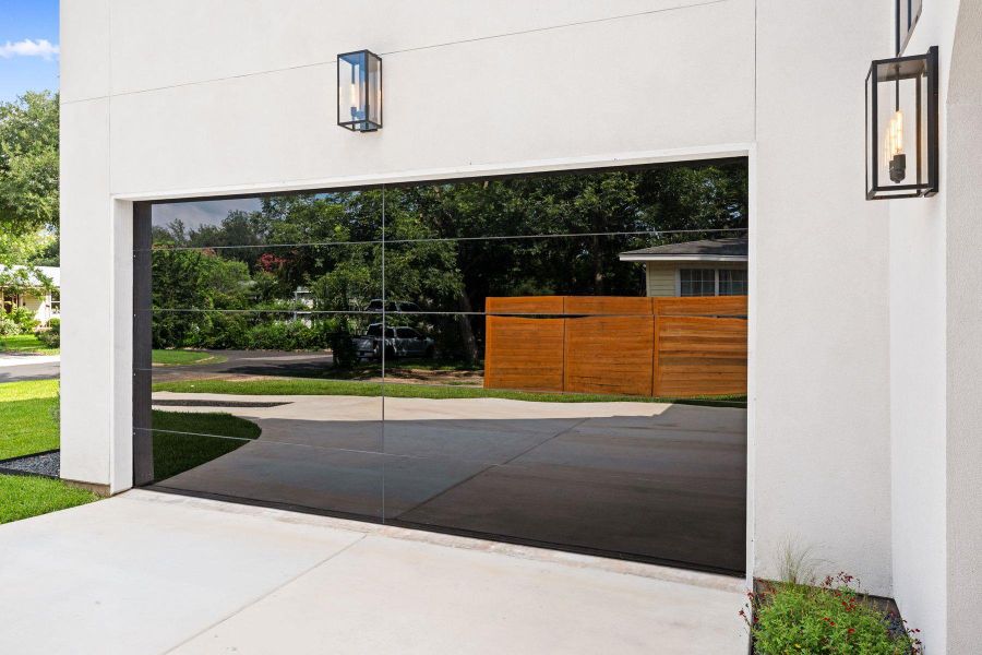 Reflective garage door enhances the modern facade with elegant outdoor lighting. Reflective garage door enhances the modern facade with elegant outdoor lighting.