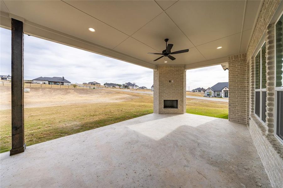 Expansive covered patio featuring a built-in fireplace, ceiling fan, recessed lighting, and a durable concrete surface