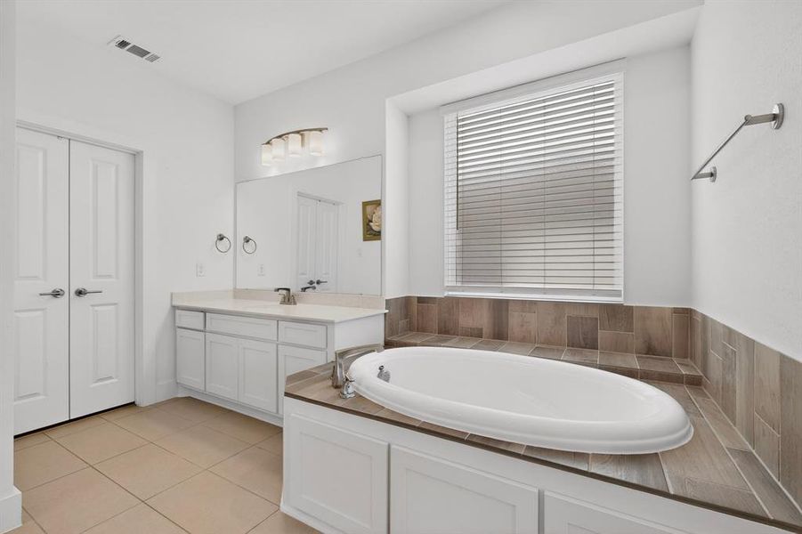 Soaking tub with surrounding wood-finish tile and window with blinds Soaking tub with surrounding wood-finish tile and window with blinds