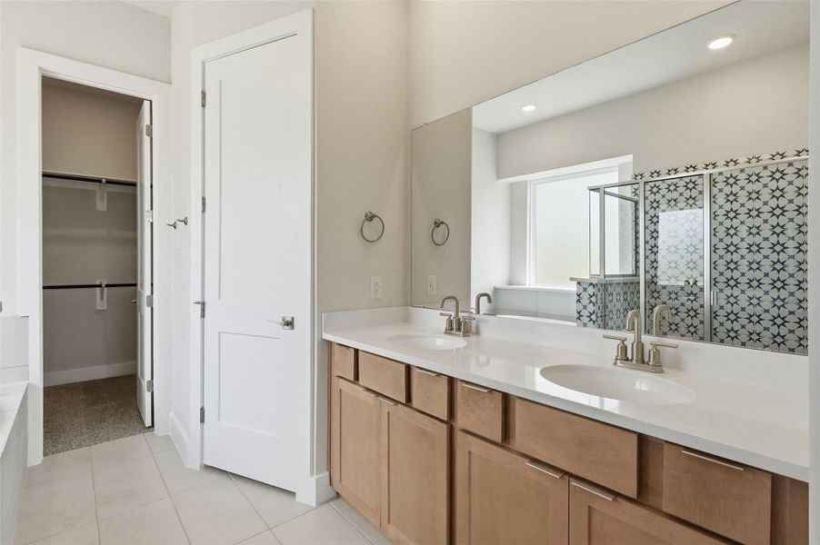 A spacious dual-sink vanity provides ample room for morning routines, featuring sleek brushed nickel fixtures and a crisp, clean aesthetic.