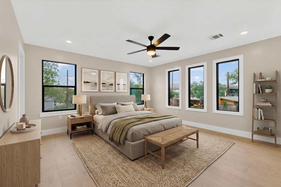 A tranquil bedroom retreat features a ceiling fan, ample natural light, and light hardwood flooring.