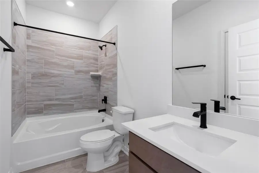 This move-in ready primary bathroom offers a spacious tub/shower combination with a tiled surround, stained cabinetry topped with light countertops, high ceilings, neutral paint, a mirror, and sleek, modern finishes for a polished look. This move-in ready primary bathroom offers a spacious tub/shower combination with a tiled surround, stained cabinetry topped with light countertops, high ceilings, neutral paint, a mirror, and sleek, modern finishes for a polished look.