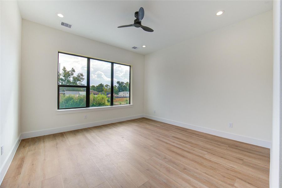 Spacious primary bedroom with large windows for abundant natural light, sleek ceiling fan, and elegant floors. Spacious primary bedroom with large windows for abundant natural light, sleek ceiling fan, and elegant floors.