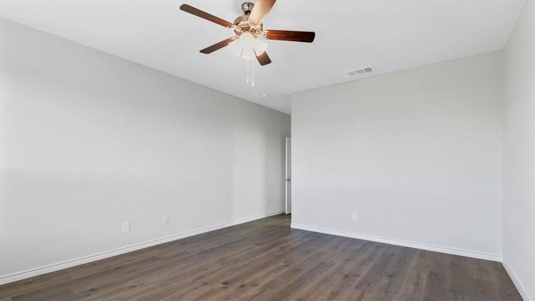Spacious room with wood-finish flooring, light gray walls, and a ceiling fan with integrated lighting
