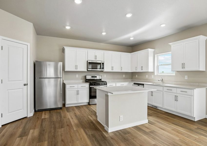 The kitchen has stainless steel appliances and plank flooring.