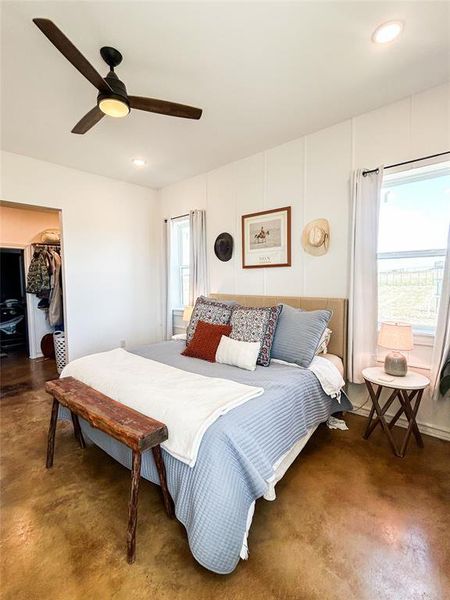 Bedroom with a ceiling fan, a spacious closet, finished concrete floors, and recessed lighting Bedroom with a ceiling fan, a spacious closet, finished concrete floors, and recessed lighting