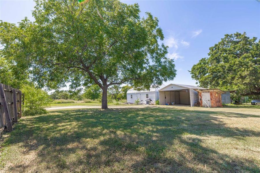 View of yard featuring a detached carport and an outbuilding View of yard featuring a detached carport and an outbuilding