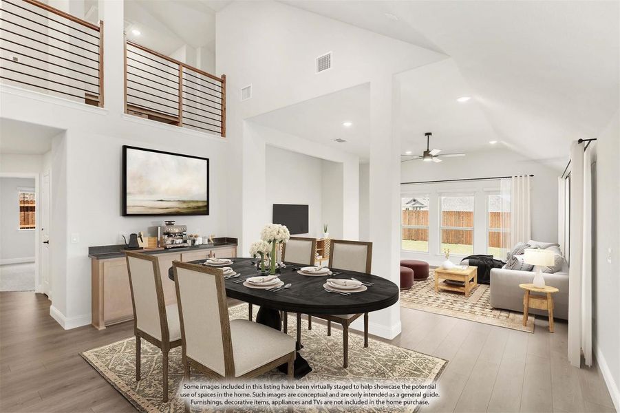 Open-concept dining area with dark oval table, high ceilings, second-floor overlook, and adjacent living room with large windows Open-concept dining area with dark oval table, high ceilings, second-floor overlook, and adjacent living room with large windows