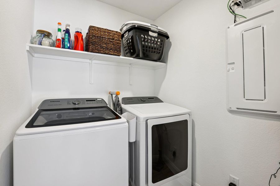 Laundry room with a wall-mounted shelf, a washer, and a dryer