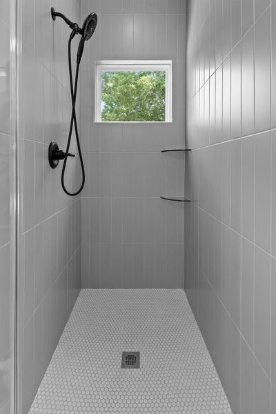 A well-appointed shower stall features sleek tiling and natural light.
