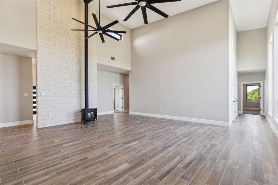 Living room featuring baseboards, a wood stove, high vaulted ceiling, electrical outlet in the floor and ceiling fan. Living room featuring baseboards, a wood stove, high vaulted ceiling, electrical outlet in the floor and ceiling fan.