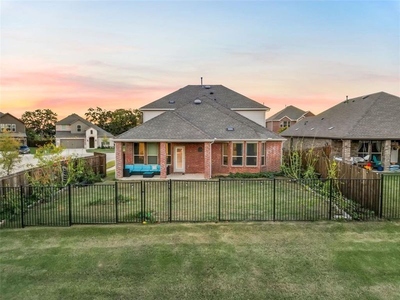 Back house at dusk with outdoor lounge area, a yard, and a patio