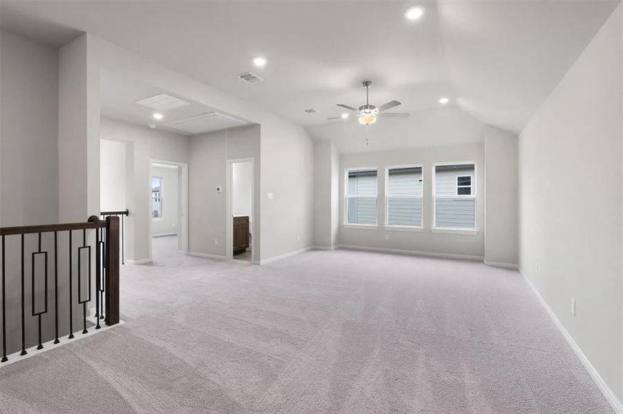 A spacious secondary living area features high ceilings, soft carpeting, and abundant natural light.