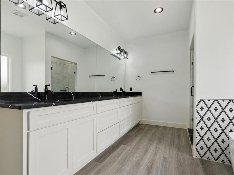 Bathroom with hardwood / wood-style floors, a shower with shower door, and dual vanity