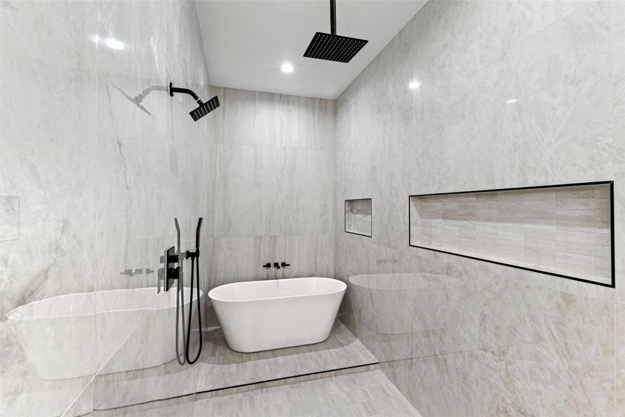This bathroom features a sleek, modern design with large marble-patterned tiles, a freestanding tub, dual rainfall showerheads, and built-in shower niches for storage, creating a luxurious and minimalist space. This bathroom features a sleek, modern design with large marble-patterned tiles, a freestanding tub, dual rainfall showerheads, and built-in shower niches for storage, creating a luxurious and minimalist space.