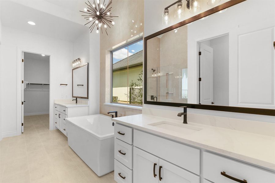 Bathroom featuring a freestanding tub, dual vanities with white cabinetry, and a large window providing ample natural light