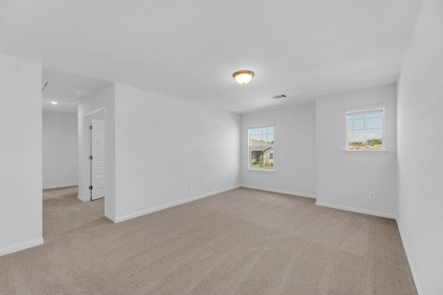 Unfurnished room with attic access, light colored carpet, and plenty of natural light Unfurnished room with attic access, light colored carpet, and plenty of natural light