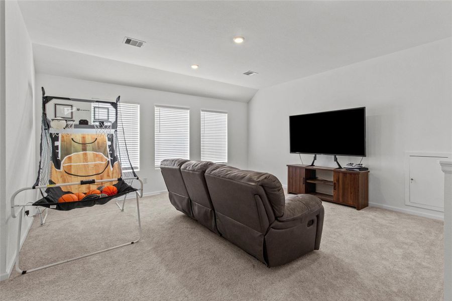 Spacious entertainment room featuring comfortable seating, a large TV, and an indoor basketball game, perfect for family fun and relaxation. Spacious entertainment room featuring comfortable seating, a large TV, and an indoor basketball game, perfect for family fun and relaxation.