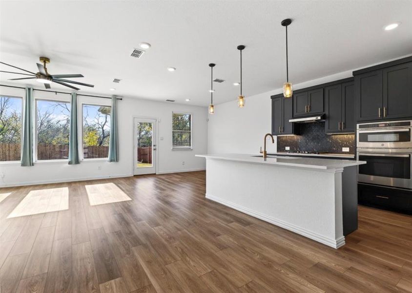 Kitchen with hanging light fixtures, open floor plan, dark cabinets, decorative backsplash, and recessed lighting