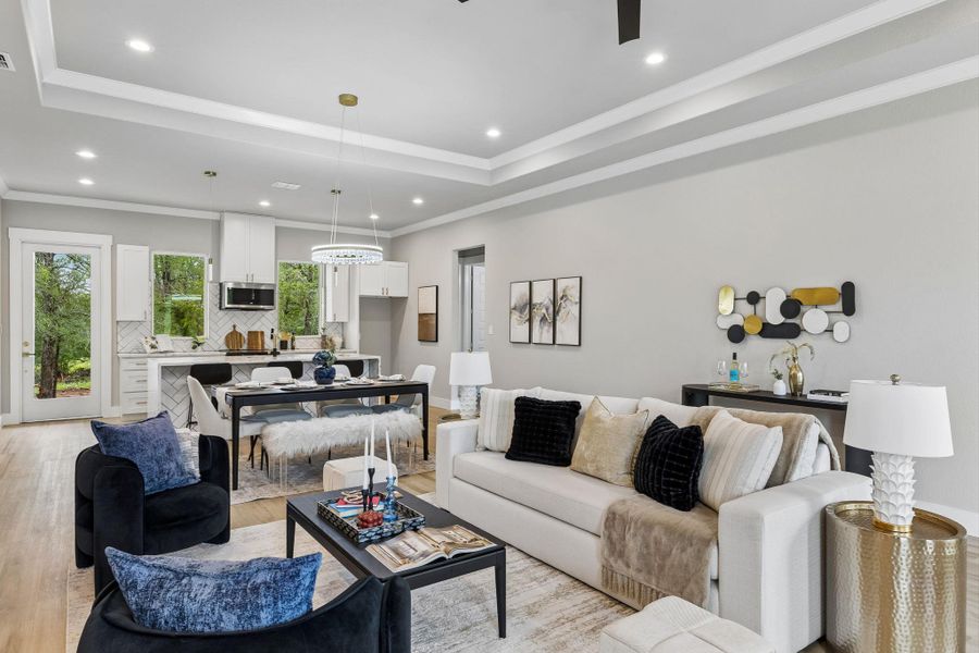 An open-concept living area flows seamlessly into the kitchen and dining spaces, featuring tray ceilings with recessed lighting.